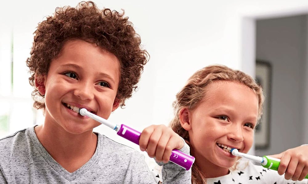 deux enfants utilisent une brosse à dents électrique